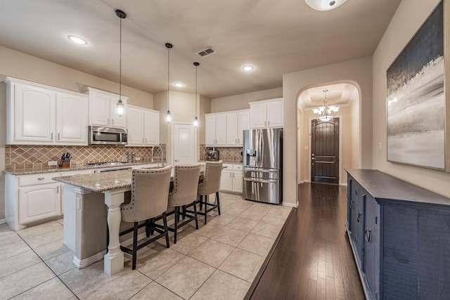 kitchen featuring arched walkways, visible vents, white cabinets, and appliances with stainless steel finishes