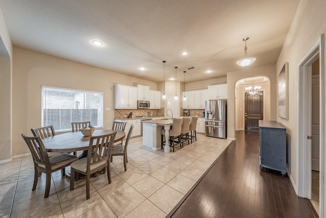 dining area featuring recessed lighting, baseboards, arched walkways, and light wood finished floors