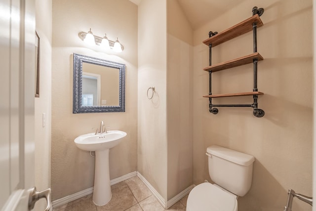 half bathroom featuring tile patterned floors, toilet, and baseboards