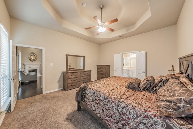 bedroom featuring visible vents, baseboards, a fireplace, a raised ceiling, and carpet flooring