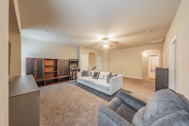 living room with a ceiling fan, carpet flooring, visible vents, and arched walkways