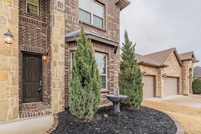 doorway to property featuring brick siding, concrete driveway, and an attached garage