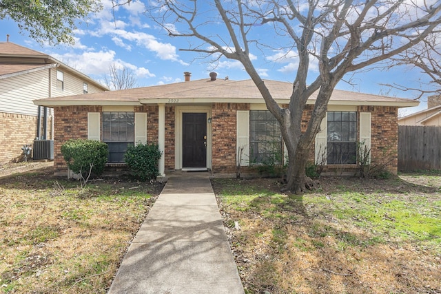 view of front of home with brick siding, central AC, and fence