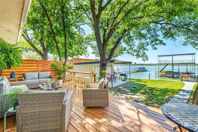 deck featuring fence, a dock, a water view, outdoor lounge area, and a lawn