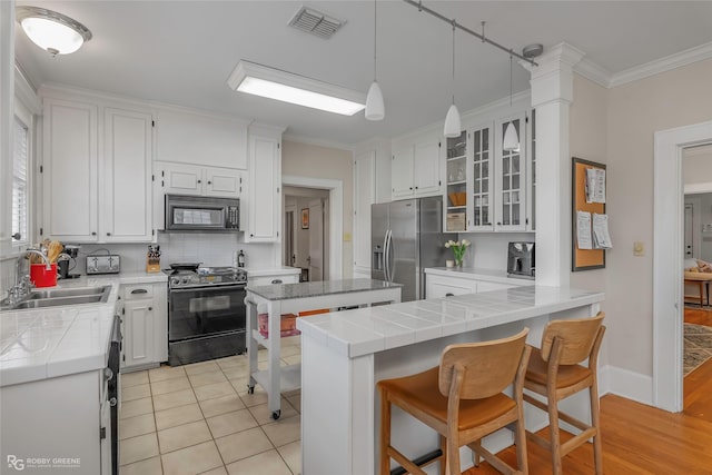 kitchen with a sink, electric range oven, tile counters, black microwave, and stainless steel fridge