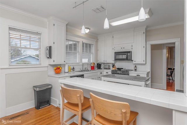 kitchen with visible vents, black microwave, gas range oven, white cabinetry, and a sink