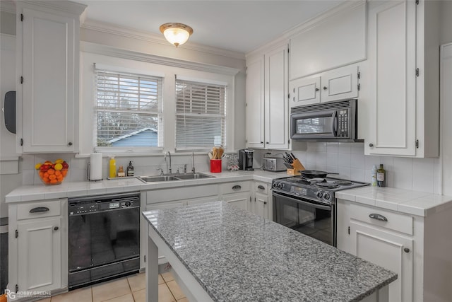 kitchen with decorative backsplash, white cabinets, black appliances, and a sink