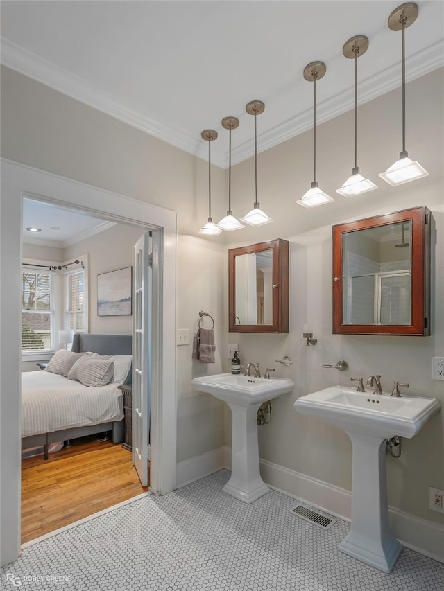 ensuite bathroom with visible vents, baseboards, ornamental molding, ensuite bathroom, and a sink