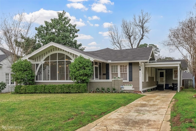 view of front of property with an attached carport, a shingled roof, concrete driveway, a front yard, and a sunroom