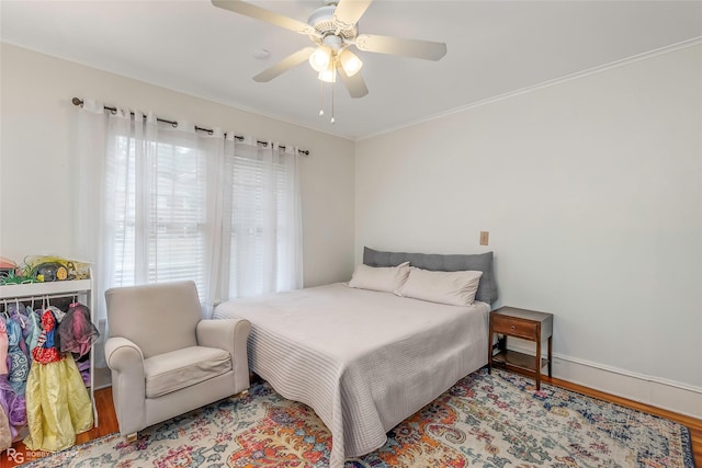 bedroom featuring multiple windows, baseboards, a ceiling fan, and wood finished floors