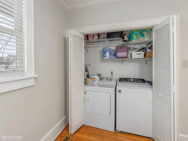 laundry area featuring baseboards, washing machine and clothes dryer, laundry area, light wood-style flooring, and crown molding