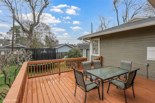 deck featuring outdoor dining space, a trampoline, and fence