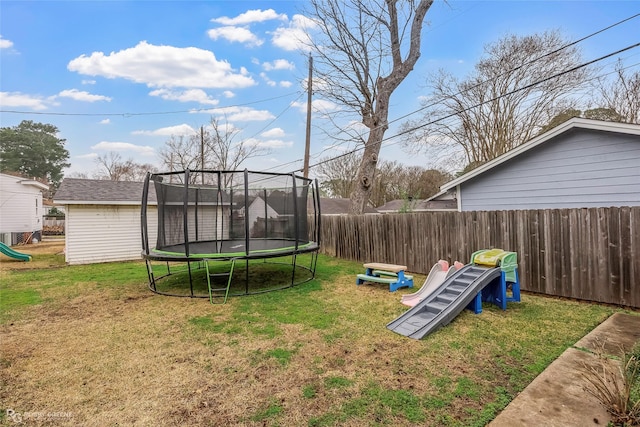 view of yard featuring a playground, a trampoline, and fence