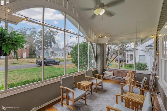 sunroom featuring a residential view, a healthy amount of sunlight, and ceiling fan