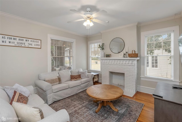 living room featuring wood finished floors, crown molding, baseboards, a brick fireplace, and ceiling fan