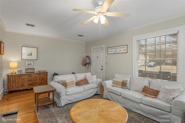 living room featuring visible vents, light wood-style flooring, ceiling fan, and ornamental molding