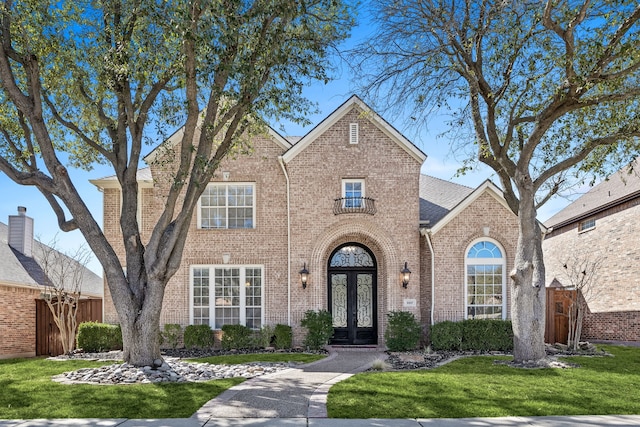 traditional home featuring brick siding, french doors, and a front yard