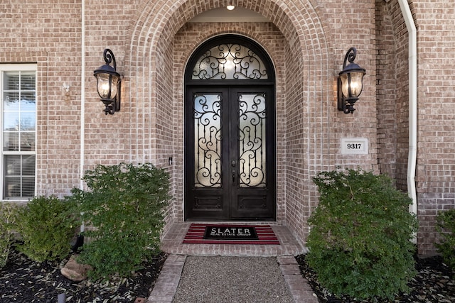 view of exterior entry featuring french doors and brick siding