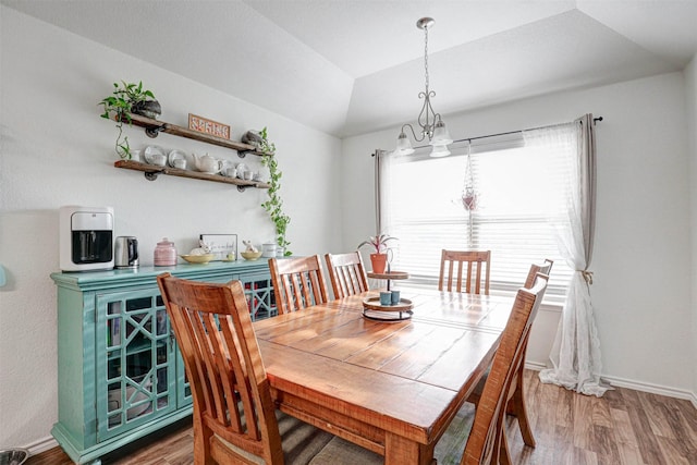 dining area with vaulted ceiling, baseboards, and wood finished floors