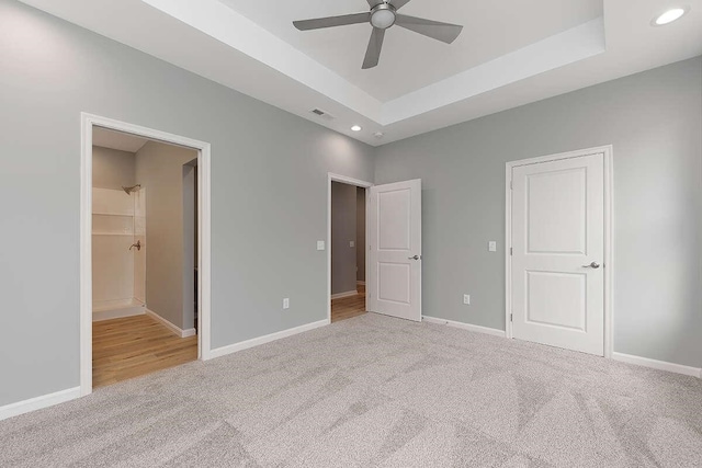 unfurnished bedroom featuring a tray ceiling, baseboards, visible vents, and carpet floors