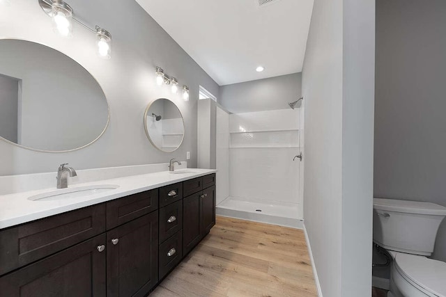 full bathroom featuring a shower, toilet, wood finished floors, and a sink