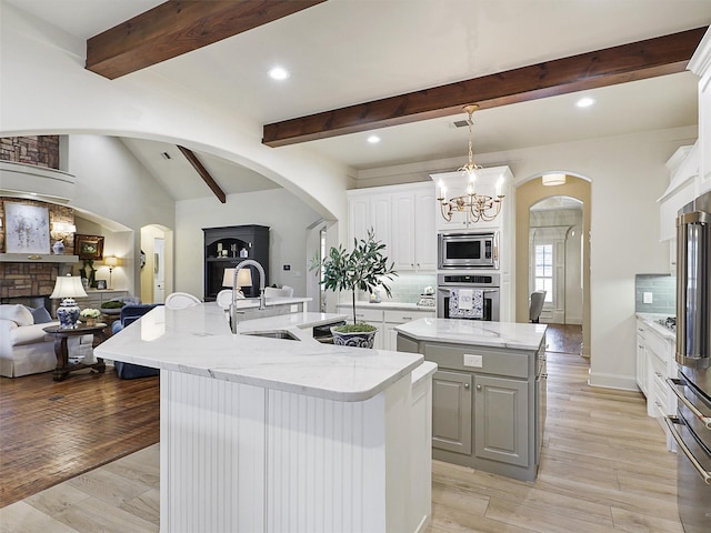 kitchen featuring a sink, an island with sink, open floor plan, and stainless steel appliances