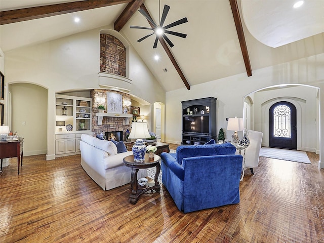 living area featuring arched walkways, high vaulted ceiling, wood finished floors, and a fireplace