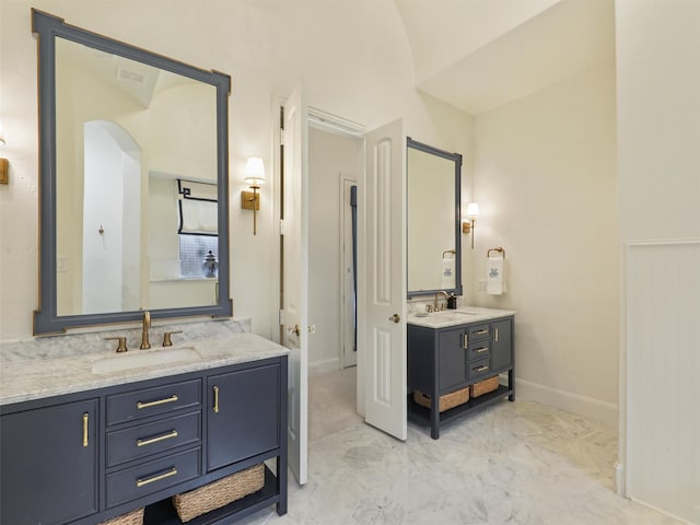 full bath featuring a sink, visible vents, baseboards, and two vanities