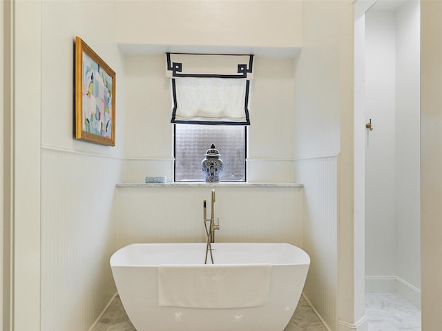 full bathroom with wainscoting, marble finish floor, and a freestanding bath