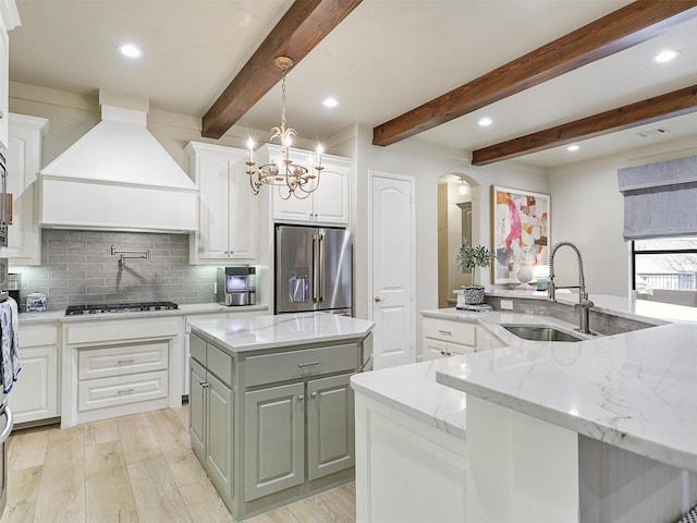 kitchen featuring premium range hood, high end fridge, an island with sink, a sink, and gas stovetop