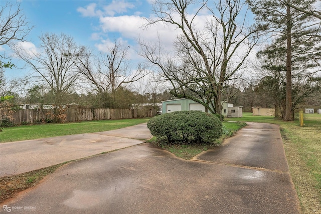 view of yard with a detached garage, an outbuilding, and fence