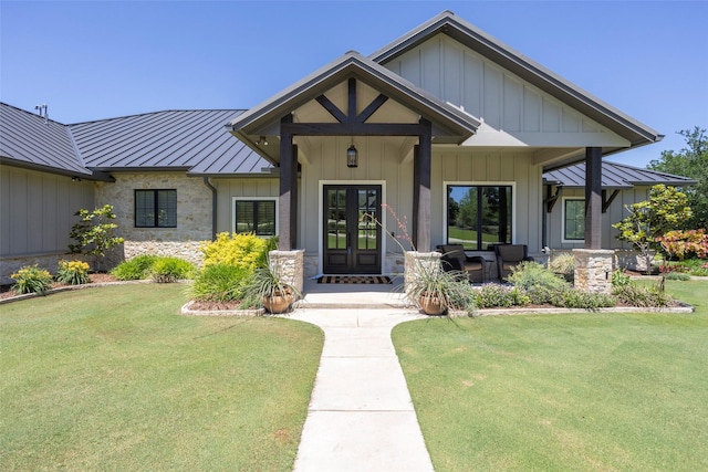 view of front of home with a standing seam roof, board and batten siding, french doors, and a front yard