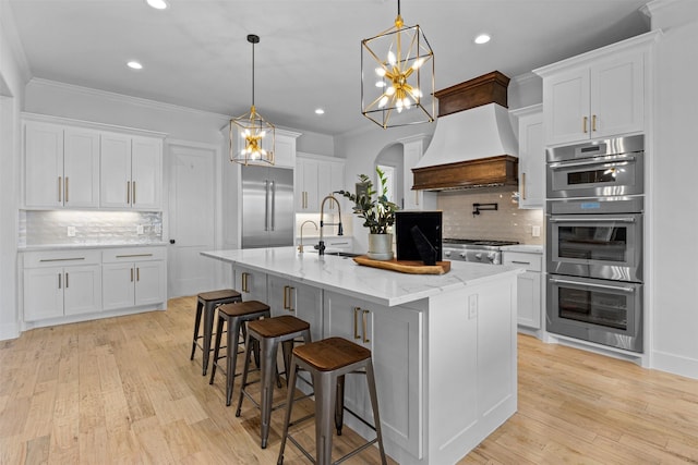 kitchen with custom exhaust hood, appliances with stainless steel finishes, white cabinets, and crown molding