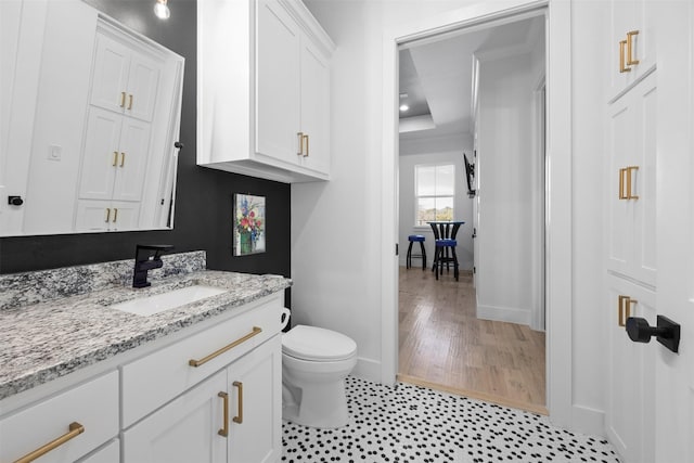 bathroom featuring a tray ceiling, baseboards, toilet, and vanity