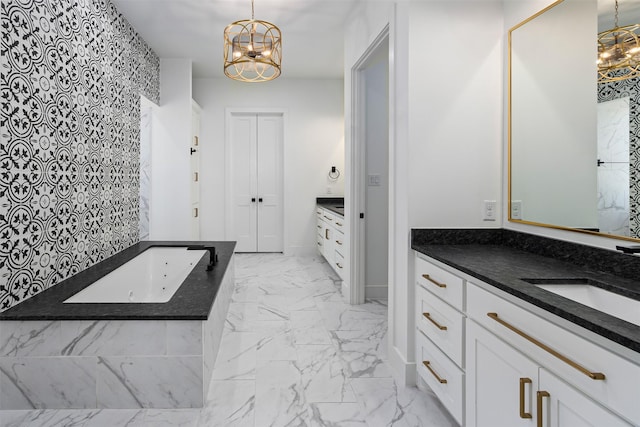 full bath with a notable chandelier, marble finish floor, vanity, and a whirlpool tub