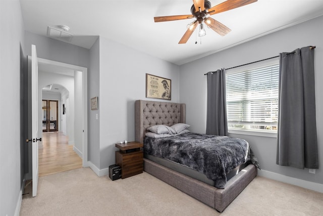 carpeted bedroom with baseboards, arched walkways, and ceiling fan