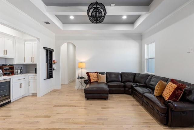 living room featuring visible vents, arched walkways, indoor wet bar, beverage cooler, and light wood-style flooring