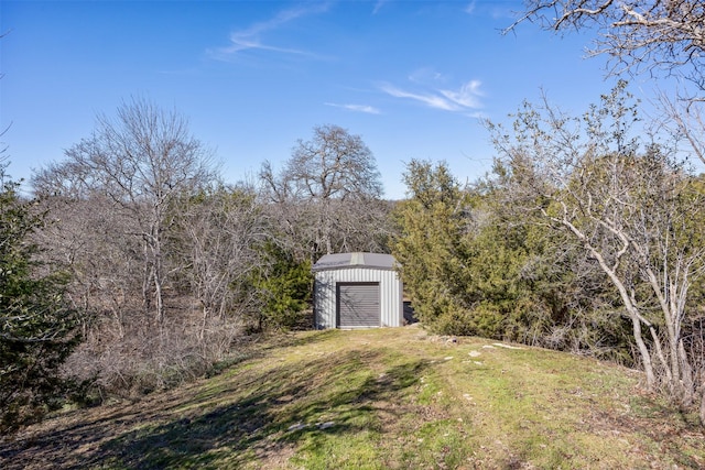 view of yard with an outdoor structure and a wooded view