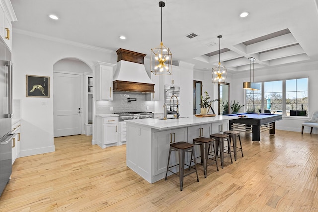 kitchen with custom exhaust hood, white cabinets, coffered ceiling, and tasteful backsplash