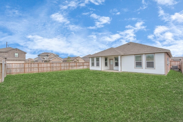 back of house with a patio, a lawn, roof with shingles, and a fenced backyard