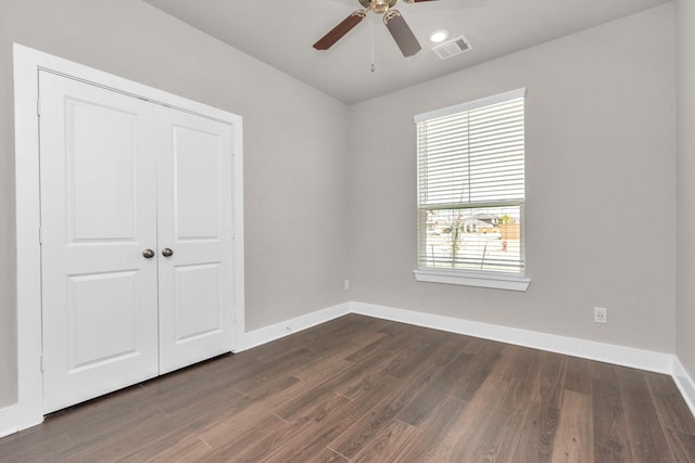 unfurnished bedroom featuring visible vents, baseboards, a closet, and dark wood-style flooring