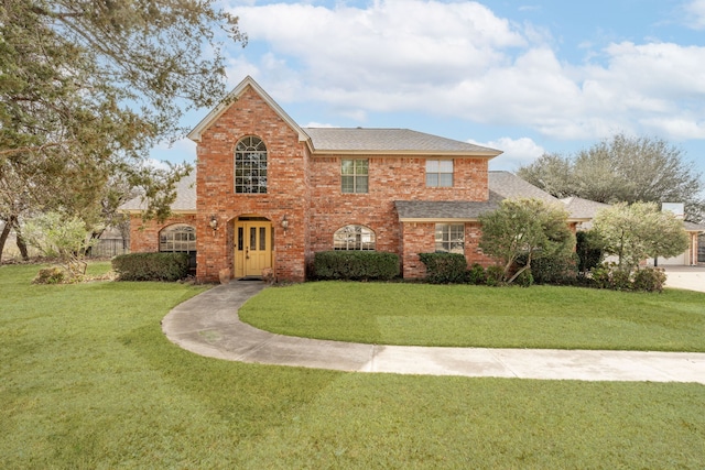 view of front facade featuring a front yard, brick siding, and a shingled roof