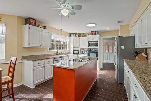 kitchen featuring a kitchen island, visible vents, black appliances, and wood finish floors