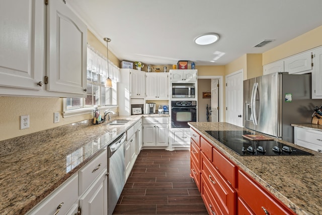 kitchen with light stone counters, visible vents, wood finish floors, a sink, and black appliances