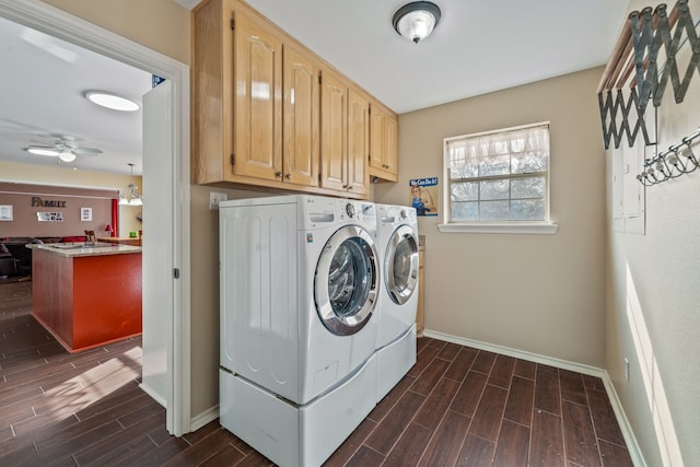 washroom featuring wood tiled floor, cabinet space, baseboards, and washer and clothes dryer