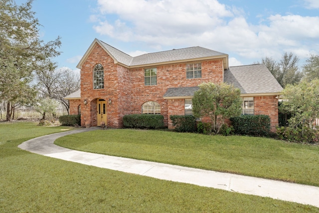 view of front of house featuring brick siding, a shingled roof, and a front lawn