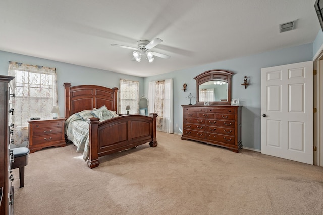 bedroom featuring a ceiling fan, light colored carpet, and visible vents