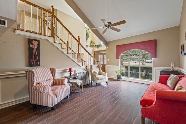 living area featuring wood finished floors, visible vents, a wainscoted wall, a ceiling fan, and stairs