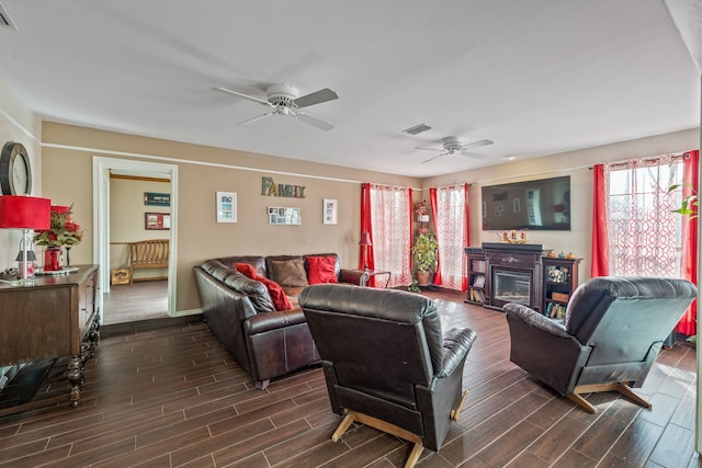 living room with visible vents, a ceiling fan, wood finish floors, and a glass covered fireplace