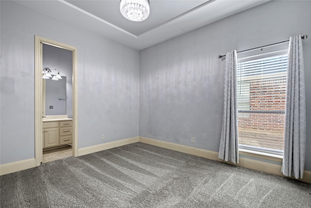 unfurnished bedroom featuring baseboards, carpet floors, ensuite bath, and a chandelier